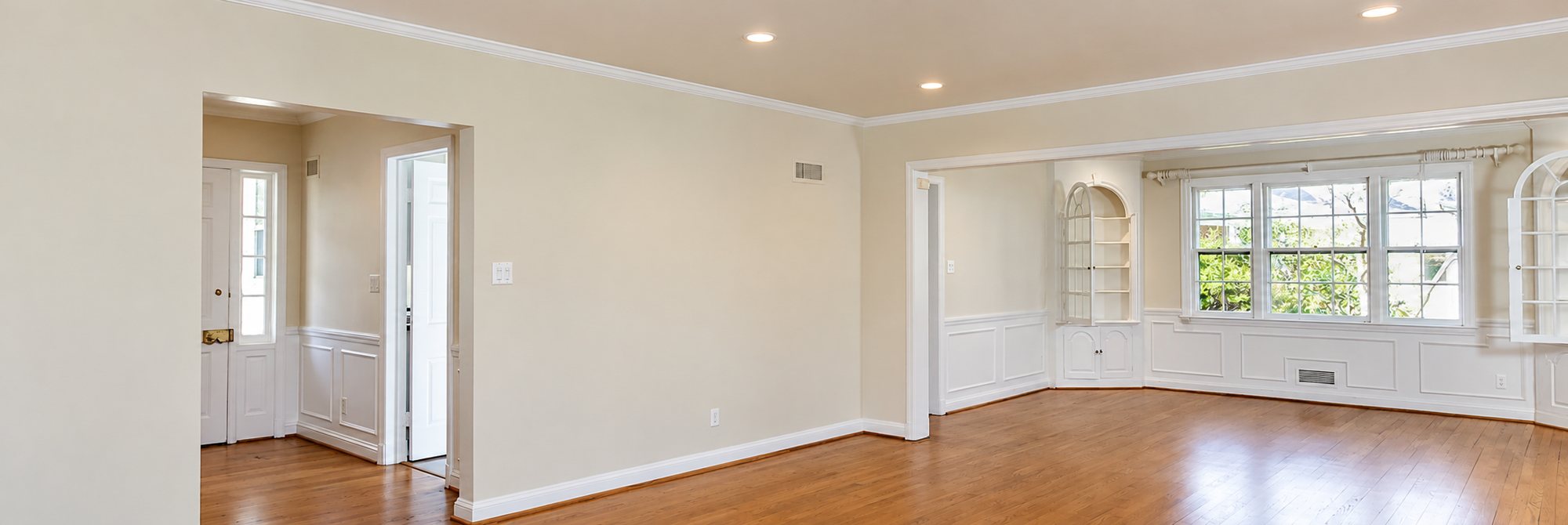 Salon vide rénové avec parquet en bois et boiseries blanches
